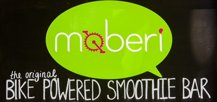 the moberi logo on a sign attached to the moberi cart which reads the original bike-powered smoothie bar