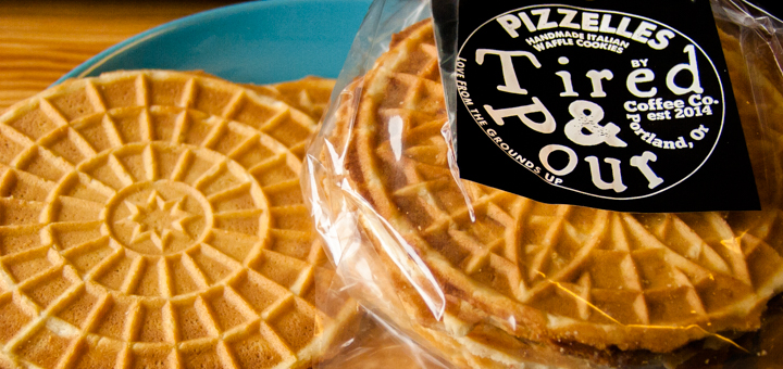 Tired & Pour logo imprinted on a sticker label adhering to a clear cellophane bag of pizzelles